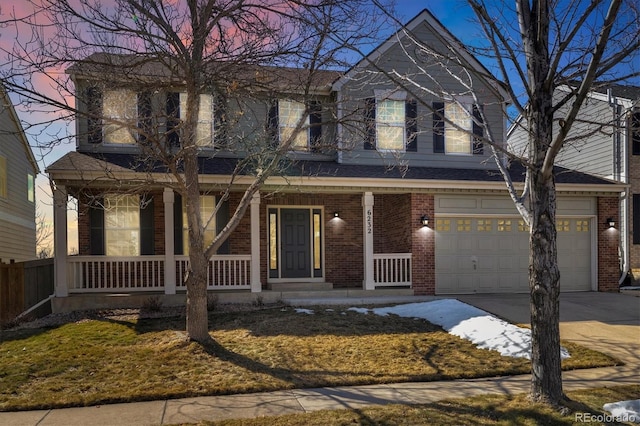 traditional-style home with a porch, brick siding, driveway, and an attached garage