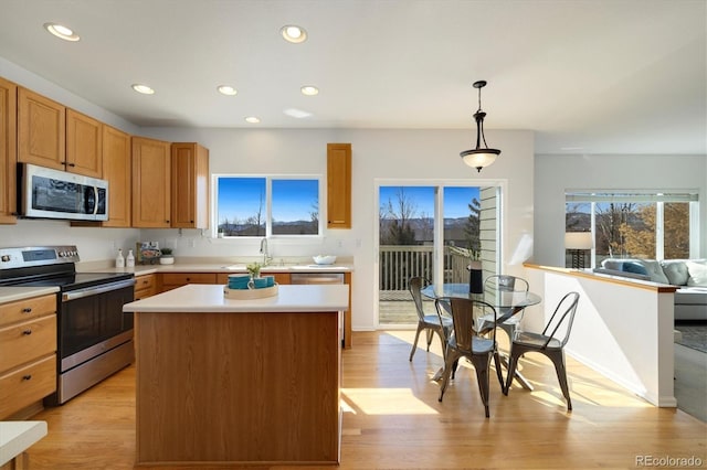 kitchen with appliances with stainless steel finishes, light countertops, light wood-type flooring, a sink, and recessed lighting