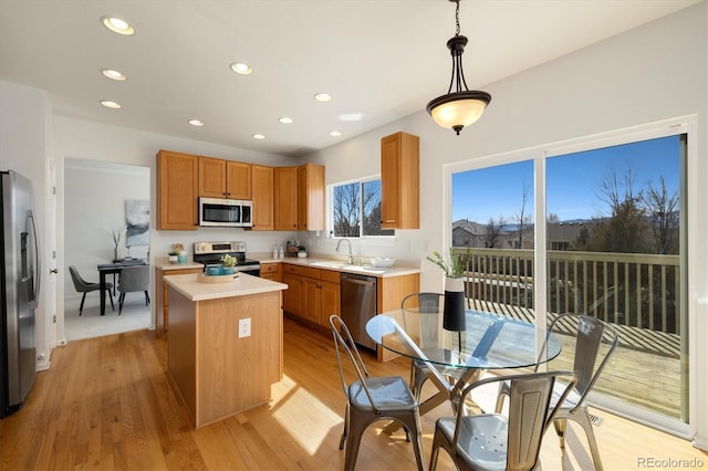 kitchen with a kitchen island, appliances with stainless steel finishes, light countertops, light wood-style floors, and a sink