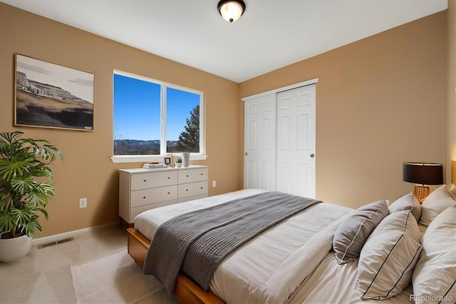 bedroom featuring light carpet, a closet, visible vents, and baseboards