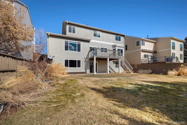 rear view of house featuring a deck, a yard, stairway, and fence