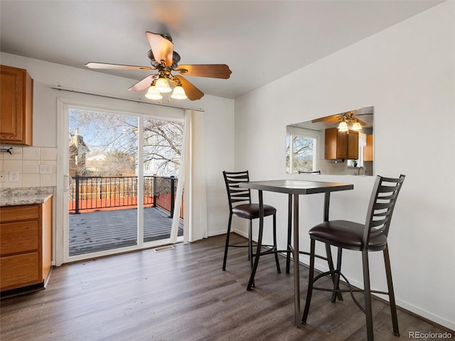 dining area featuring ceiling fan, dark wood-type flooring, and a healthy amount of sunlight