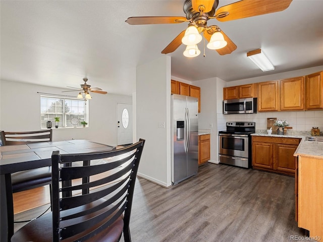 kitchen featuring dark hardwood / wood-style flooring, stainless steel appliances, ceiling fan, and tasteful backsplash