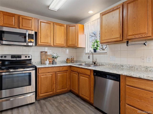 kitchen with light stone countertops, stainless steel appliances, decorative backsplash, dark hardwood / wood-style flooring, and sink