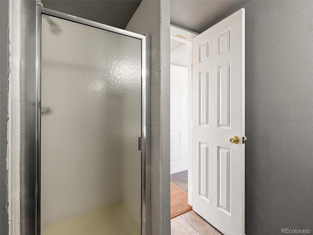 bathroom with an enclosed shower and hardwood / wood-style floors