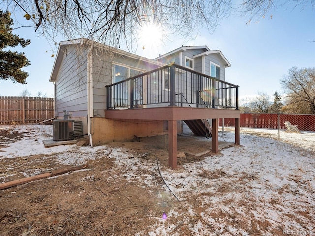 snow covered rear of property with central air condition unit and a wooden deck