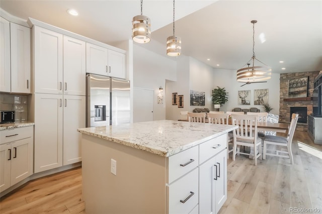 kitchen with pendant lighting, stainless steel fridge, white cabinets, and a kitchen island