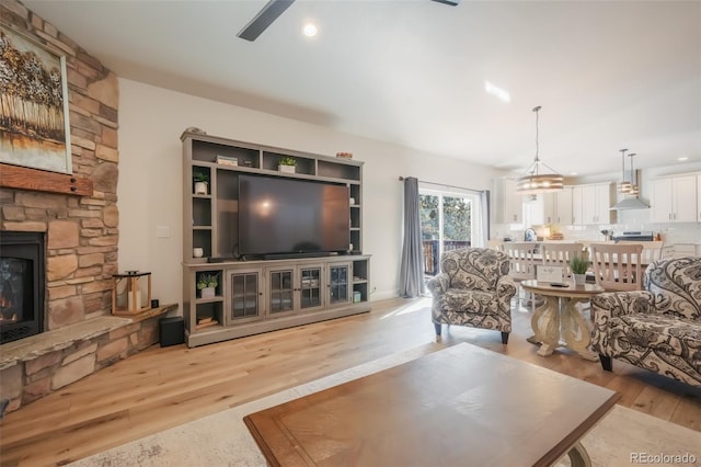 living room with a stone fireplace and light hardwood / wood-style floors