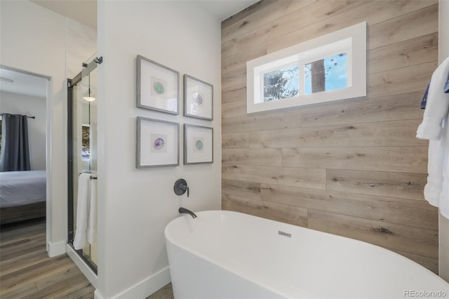 bathroom featuring hardwood / wood-style flooring, a bath, and wood walls