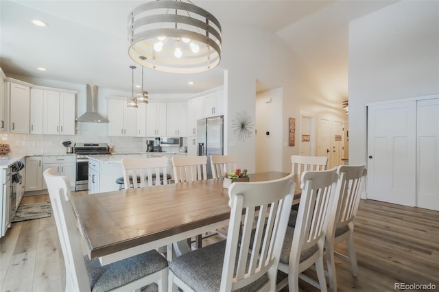 dining room with light hardwood / wood-style flooring and a high ceiling