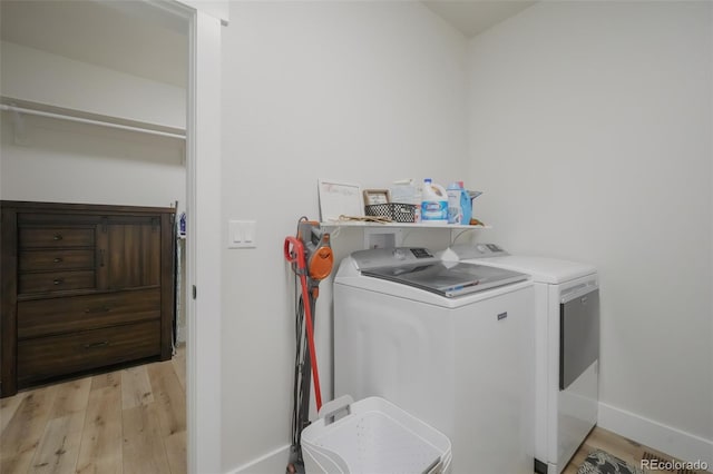 laundry room with light wood-type flooring and washer and clothes dryer