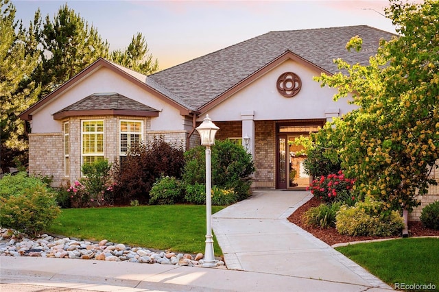 3231 Oak St, Wheat Ridge, CO 80033 - view of front of house featuring stucco siding, a yard, brick siding, and a shingled roof