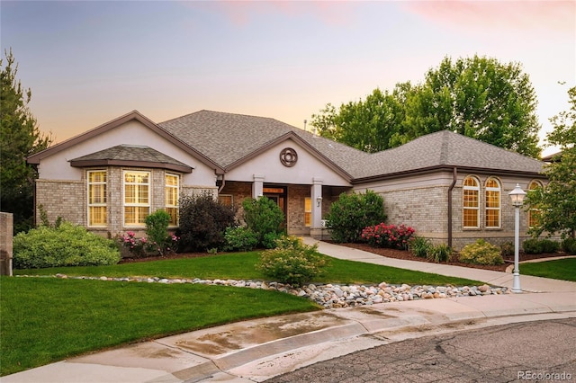 3231 Oak St, Wheat Ridge, CO 80033 - view of front of home with brick siding, a front yard, stucco siding, and a shingled roof