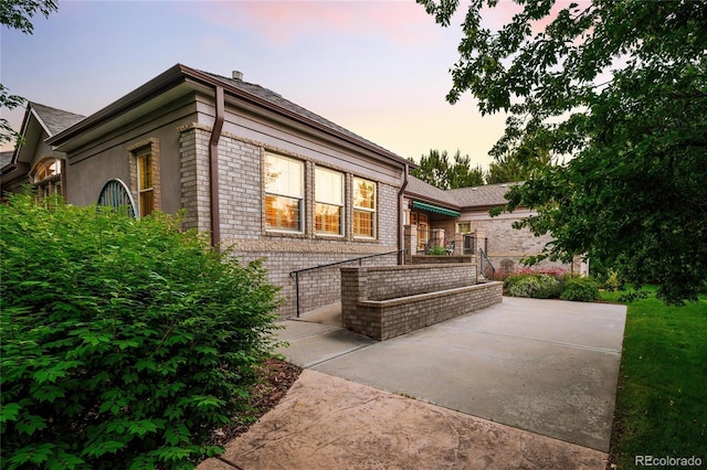 3231 Oak St, Wheat Ridge, CO 80033 - back of property at dusk featuring brick siding and a patio