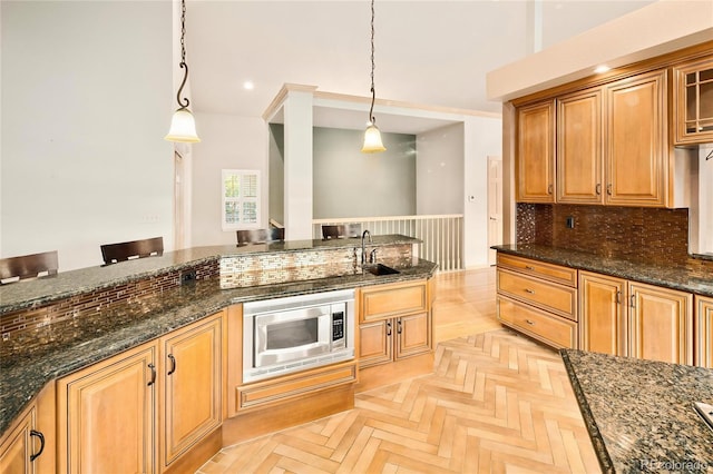 3231 Oak St, Wheat Ridge, CO 80033 - kitchen featuring stainless steel microwave, decorative light fixtures, dark stone counters, backsplash, and glass insert cabinets