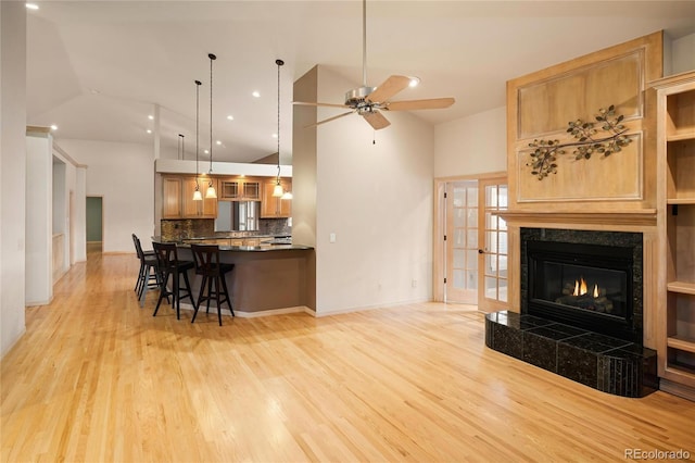 3231 Oak St, Wheat Ridge, CO 80033 - living room with light wood-style floors, a ceiling fan, a tiled fireplace, high vaulted ceiling, and recessed lighting