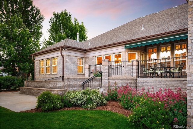 3231 Oak St, Wheat Ridge, CO 80033 - view of front of house featuring roof with shingles, a patio area, brick siding, and a yard
