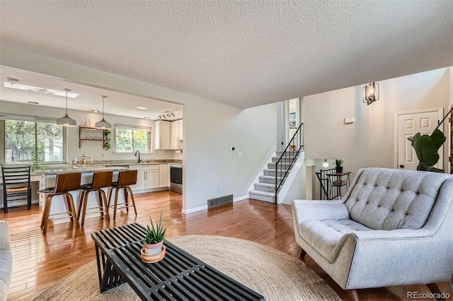 1641 S Parfet Ct, Denver, CO 80232 - living room featuring visible vents, a textured ceiling, light wood-style flooring, and stairs