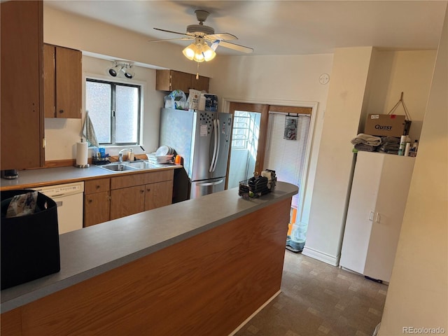 kitchen featuring a sink, freestanding refrigerator, a peninsula, dishwasher, and ceiling fan