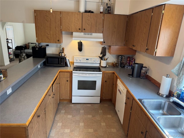 kitchen featuring brown cabinets, a sink, under cabinet range hood, white appliances, and light countertops