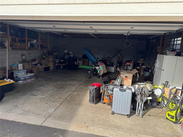 garage featuring concrete block wall and freestanding refrigerator