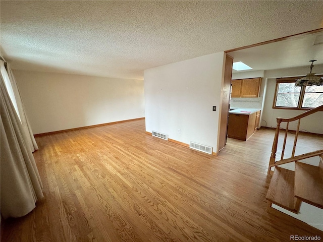 empty room with a textured ceiling and light wood-type flooring