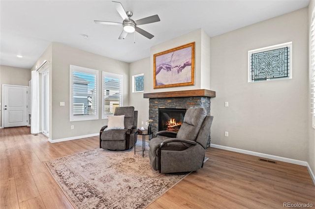 48 Mayflower Park Pl, Colorado Springs, CO 80905 - living area featuring light wood-type flooring, a stone fireplace, and a ceiling fan