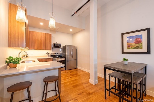 824 Grand Ave Unit 4, Grand Lake, CO 80447 - kitchen featuring stainless steel appliances, a sink, light countertops, light wood-style flooring, and a kitchen bar