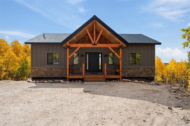 view of front of home with stone siding, board and batten siding, and roof with shingles