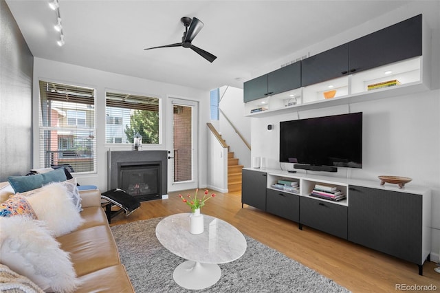 84 Spruce St Unit 707, Denver, CO 80230 - living area with stairway, a ceiling fan, light wood finished floors, a glass covered fireplace, and track lighting