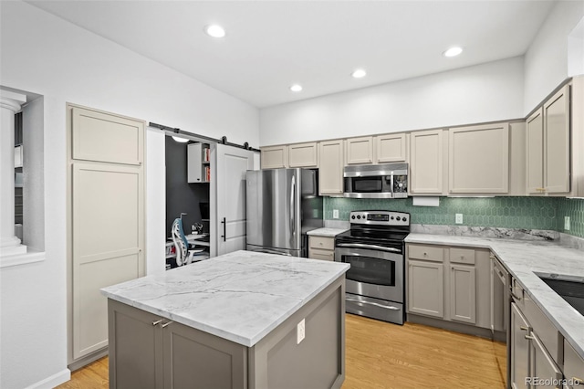 84 Spruce St Unit 707, Denver, CO 80230 - kitchen featuring appliances with stainless steel finishes, gray cabinets, a kitchen island, backsplash, and light stone counters