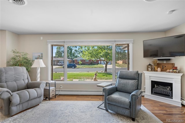 living room with hardwood / wood-style floors, a baseboard radiator, and a wealth of natural light