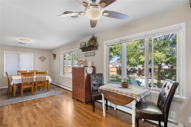 dining space with hardwood / wood-style flooring, a baseboard radiator, a wealth of natural light, and ceiling fan