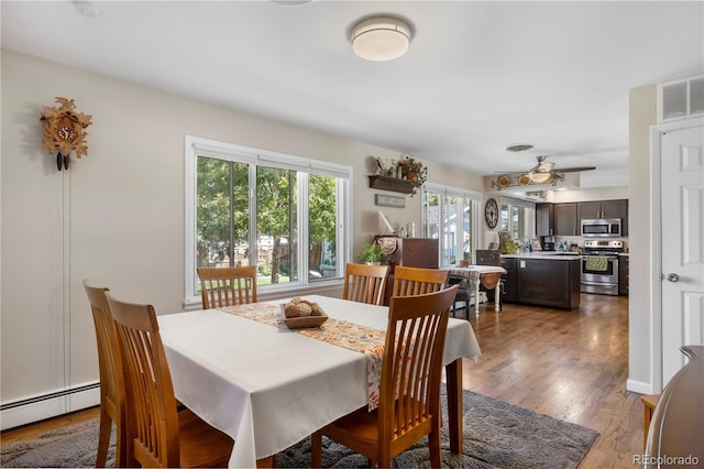 dining space with hardwood / wood-style floors and a baseboard heating unit