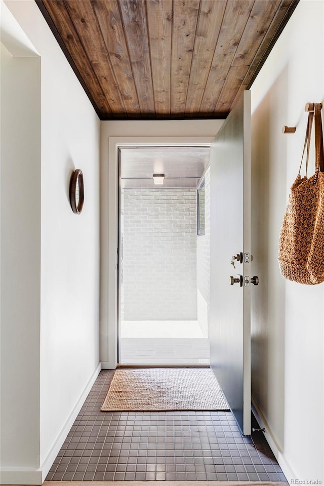 corridor featuring baseboards, wooden ceiling, and tile patterned flooring