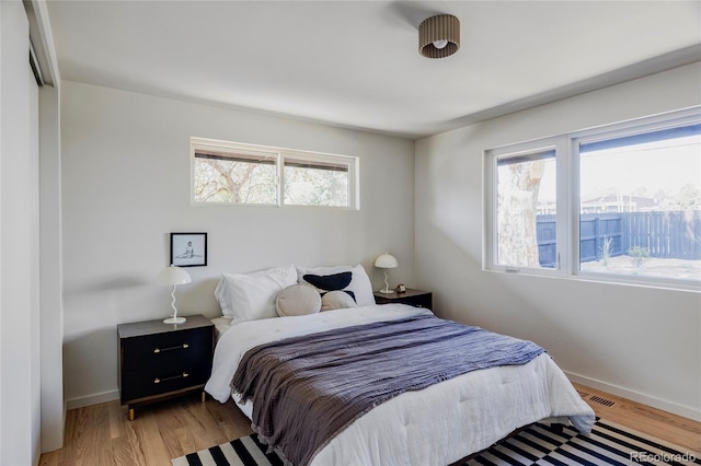 bedroom with light wood finished floors, visible vents, and baseboards