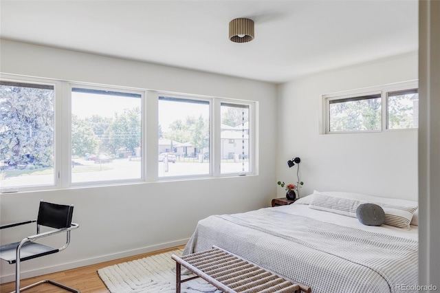 bedroom with baseboards, multiple windows, and light wood-style floors