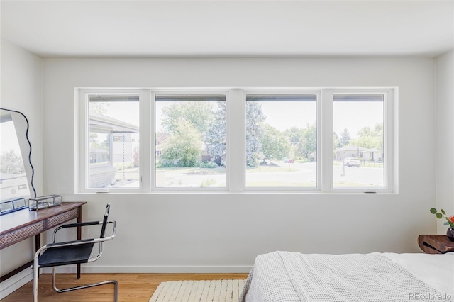 bedroom featuring multiple windows, wood finished floors, and baseboards