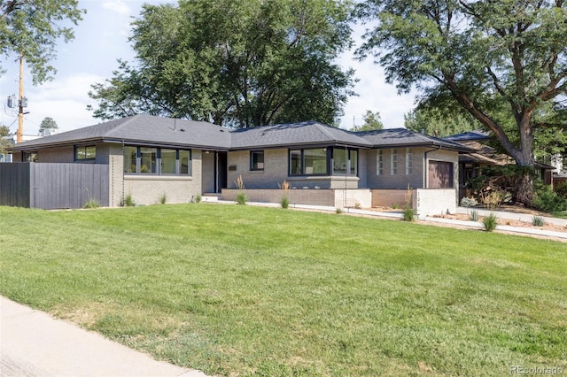 prairie-style house with a front lawn, an attached garage, fence, and brick siding