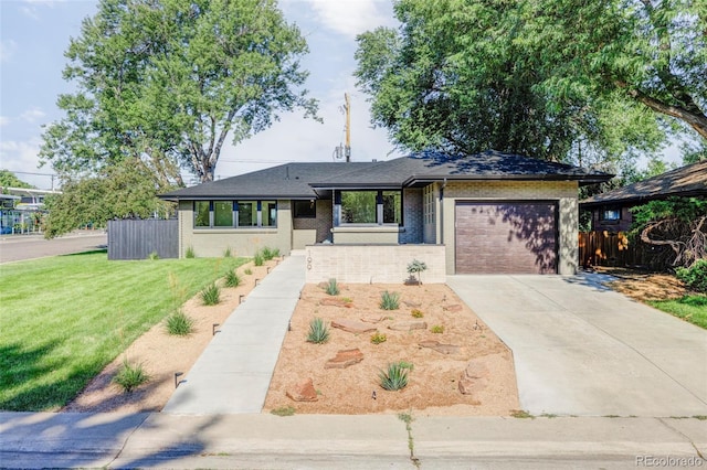 view of front of home with a garage, concrete driveway, fence, a front yard, and brick siding