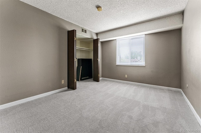 unfurnished bedroom featuring light carpet and a textured ceiling