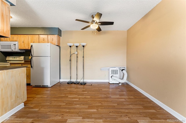 kitchen with hardwood / wood-style flooring, ceiling fan, white appliances, and a textured ceiling