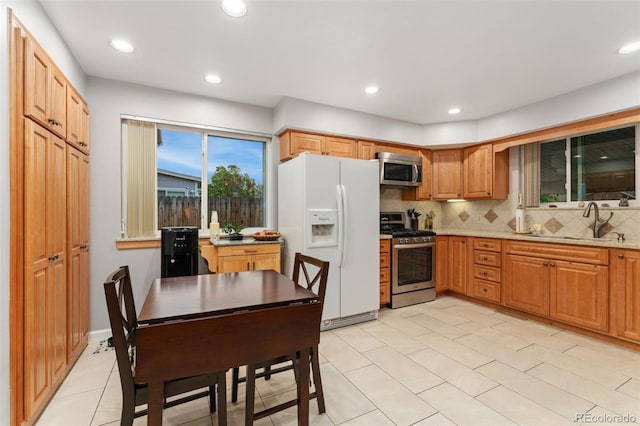 12906 Cherry Way, Thornton, CO 80241 - kitchen with stainless steel appliances, decorative backsplash, light stone counters, recessed lighting, and light tile patterned floors