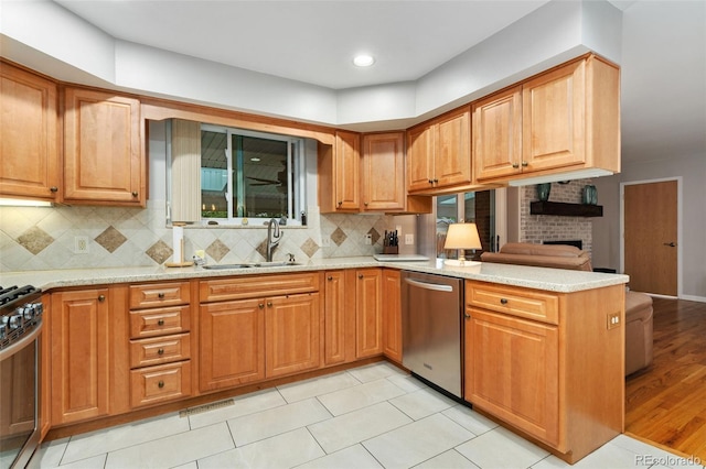 12906 Cherry Way, Thornton, CO 80241 - kitchen with appliances with stainless steel finishes, a peninsula, light stone counters, decorative backsplash, and a fireplace
