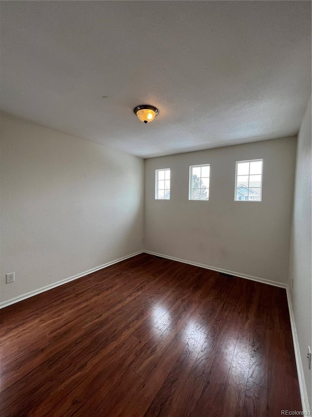 empty room featuring dark wood finished floors and baseboards