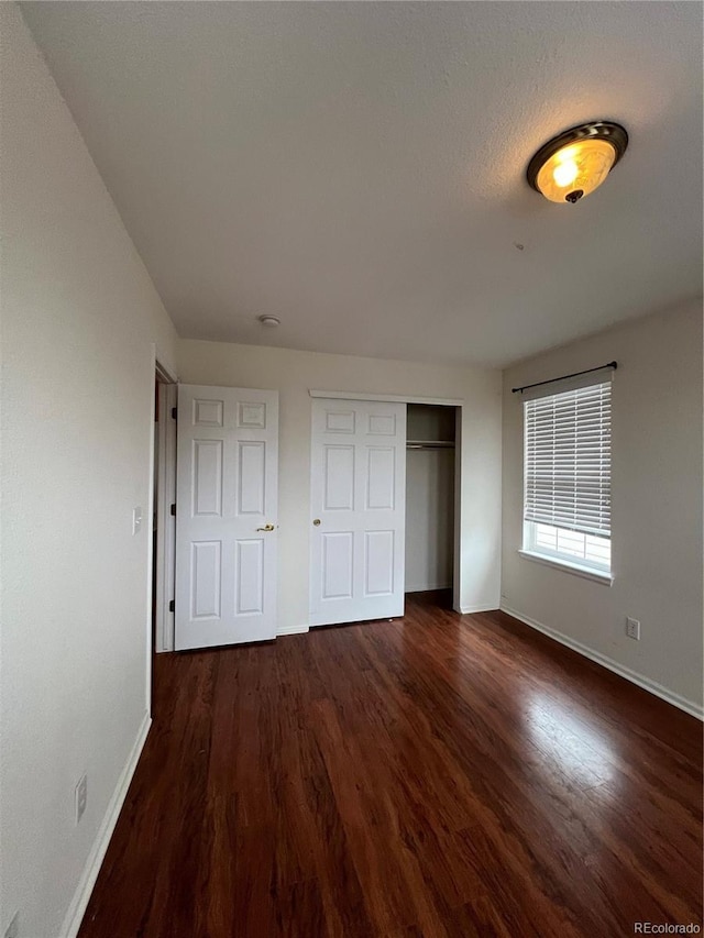 unfurnished bedroom with a closet, baseboards, and wood finished floors