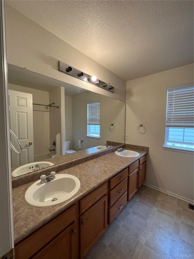 bathroom with double vanity, toilet, and a sink