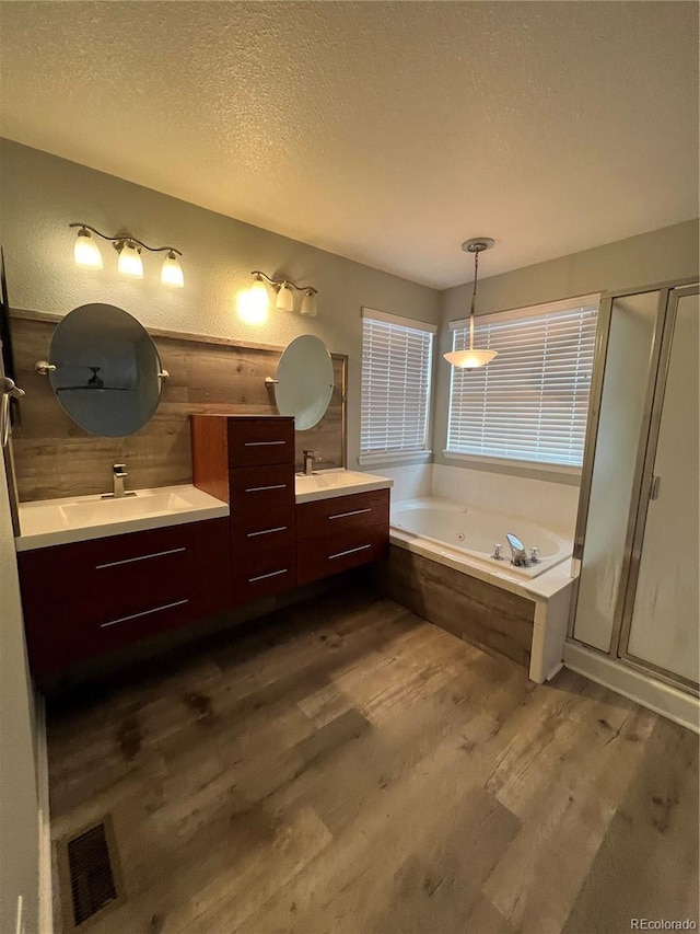 bathroom featuring visible vents, a textured ceiling, wood finished floors, a tub with jets, and a shower stall