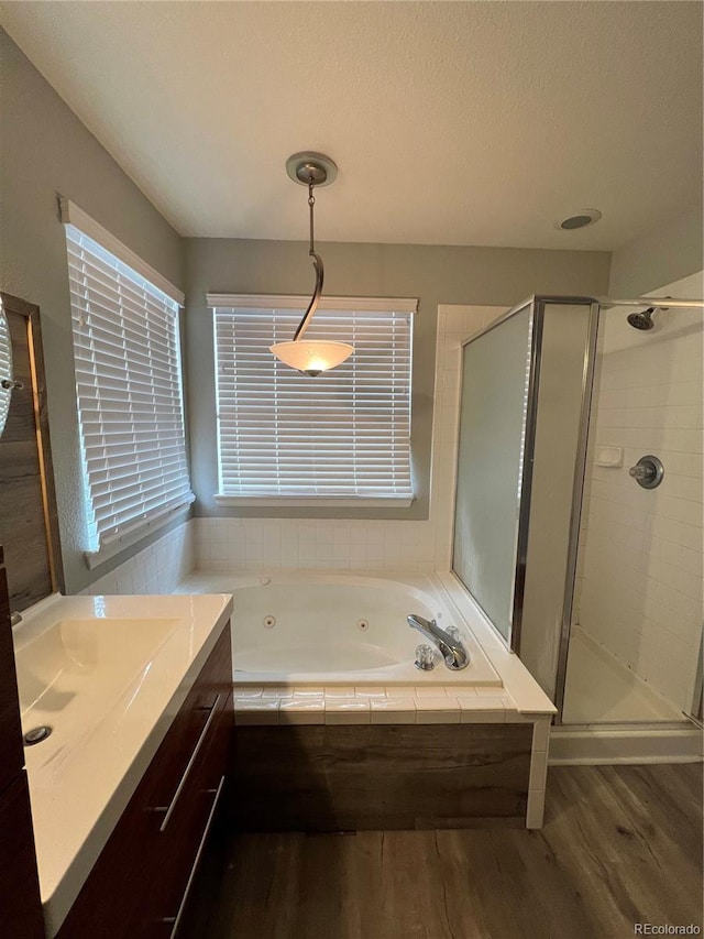 full bath featuring a stall shower, a jetted tub, vanity, and wood finished floors