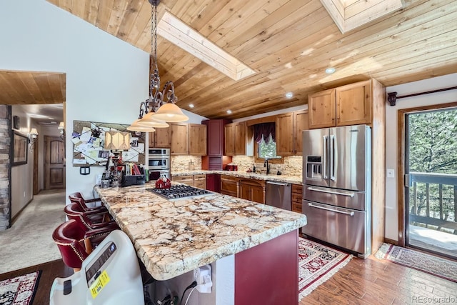 kitchen featuring wooden ceiling, a skylight, appliances with stainless steel finishes, and decorative backsplash